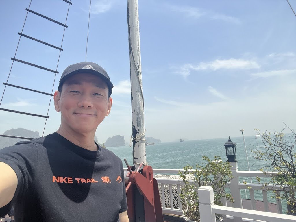 Clifford Tan smiling beside the water, shown on the right of the image